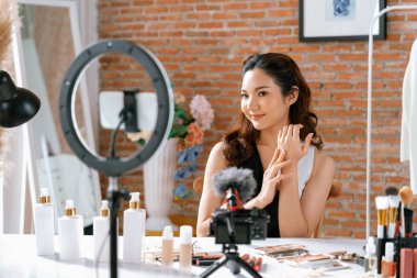 Kadın Etkilenen Vlog video görüntülerini canlı olarak çekiyor. Makyajın çoğu sosyal medya ya da blog 'u anlatıyor. Kozmetik stüdyosu ışıklandırmalı mutlu genç kız çevrimiçi pazarlama oturumu yayını için..