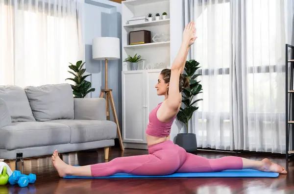 自宅での運動マットの瞑想姿勢でヨガ姿勢をしているスポーツウェアの柔軟でデクスタリティの女性 穏やかな心と静けさで健康的なヨガライフスタイル — ストック写真