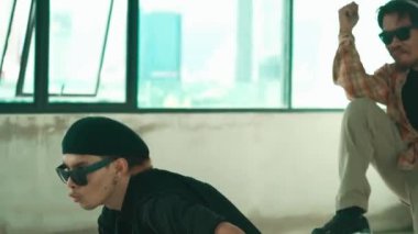 Genç yakışıklı hippi, çok kültürlü arkadaşlarla dans ederek break dans yapıyor. Happy dans takımı binadaki hip-hop müziğine geçiyor. Enerjik sokak dansı. Açık hava sporu 2024 hiphop..