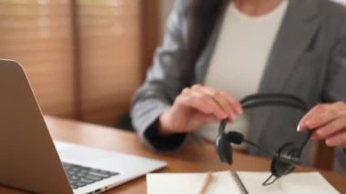 Kadın çağrı merkezi operatörü ya da müşteri hizmetleri çalışanı, müşteriye yardım etmek için kulaklıkla konuşurken çalışma alanı üzerinde çalışıyor. Profesyonel modern iş hizmeti. Blithe