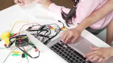 Zeki öğretmenin öğrencilere dijital elektrikli aletleri öğretmesi ve açıklaması. Kız elektronik aletleri öğreniyor ve ana kartı tamir etmek için çipleri ve kabloları yerleştiriyor. - Yakın çekim. Etkinlik.