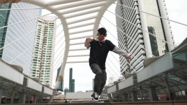 Genç Asyalı hippi şehir merkezinde insanların etrafında ayak izlerini gösteriyor. Şık bir sokak dansçısı B-boy ya da serbest dans eder. Açık hava sporu 2024. Break dans. Yumuşak bir şekilde..