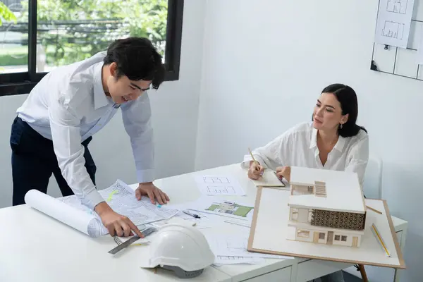 Professional architect team work together and discuss about house design with blueprint, map and architectural equipment at office. Creative business design and teamwork concept. Immaculate.