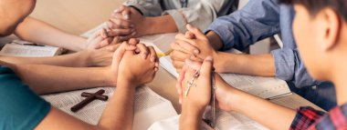 Cropped image of diversity people hand praying together at wooden church on bible book while hold hand together with believe. Concept of hope, religion, faith, god blessing concept. Burgeoning. clipart