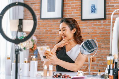 Kadın Etkilenen Vlog video görüntülerini canlı olarak çekiyor. Makyajın çoğu sosyal medya ya da blog 'u anlatıyor. Kozmetik stüdyosu ışıklandırmalı mutlu genç kız çevrimiçi pazarlama oturumu yayını için..