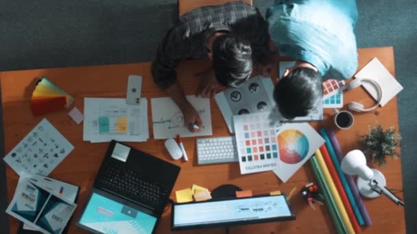 聪明设计师的自顶向下视图帮助经理从彩色调色板中选择颜色 在空中看到商人在一起工作和规划 同时从笔记本电脑上看标志 专题讨论会 — 图库视频影像