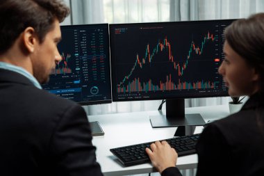 Dinamik borsada döviz kuru yatırımını tartışan iki ticaret simsarı iki bilgisayar ekranında gerçek zamanlı risk grafiği ya da modern ofisteki kar noktasını karşılaştırıyor. Varsayım.