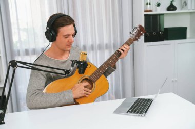 Gülümseyen yüzlü akıllı şarkıcının sunucu kanalı, şarkı söylerken gitar çalmak, sosyal medya kanalında yayın yapmak, modern stüdyo kaydında video kaydedici olarak kulaklık takmak. Bireysel.