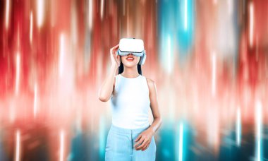 Beyaz VR kulaklık takan bir kadın ve beyaz kolsuz bağlantı metaverse, gelecekteki teknoloji siber uzay topluluğu yaratıyor. Etrafında soyut bir ışık görmek hoşuna gidiyor. Halüsinasyon.