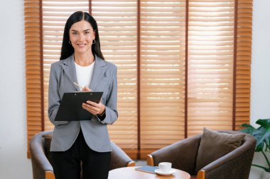 Psikiyatri ofisinde ya da terapi odasında koltukta oturan mutlu ve gülümseyen kadın psikolog portresi. Arkadaş canlısı ve profesyonel ruh sağlığı danışmanı ve terapisti. Blithe