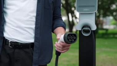 Yolculuk sırasında doğal orman ya da milli parktaki elektrikli araba için şarj olan bir adam. Tatil ve tatil boyunca çevre dostu seyahat. Yükselt