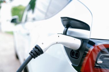 Elektrikli araç portuna bağlı EV şarj prizi kolu şarj istasyonundan şarj oluyor. Modern tasarlanmış EV araba ve daha iyi bir gelecek konsepti için temiz enerji sürdürülebilirliği. Eşzamanlama