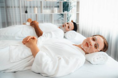 Kaplıca salonunun sakin, modern gündüz atmosferi, birkaç müşteri yüz maskesi takarak kendini yenilemeye çalışıyor. Yüz bakımı ve güzellik kozmetolojisi prosedürü. Sessiz.