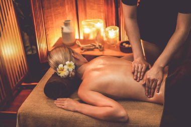 Beyaz kadın müşteri stres önleyici spa masajının keyfini çıkarıyor ve lüks otel ya da otelde sıcak mum ışığında güzellik teniyle eğleniyor. Sessiz.