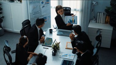 Akıllı iş kadınlarının en üst görüşü çeşitli iş adamlarına satış tablosunun arttığını gösterirken, bir grup farklı iş adamı da masada belgelerle hisse yatırım verilerini dinleyip analiz ediyor. Müdürlük.