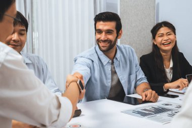 Çeşitli ofis çalışanları stratejik iş pazarlama toplantısı üzerine anlaşma yaptıktan sonra el sıkışıyor. Takım çalışması ve olumlu tutum verimli ve destekleyici bir iş yeri yaratır. Tedbirli