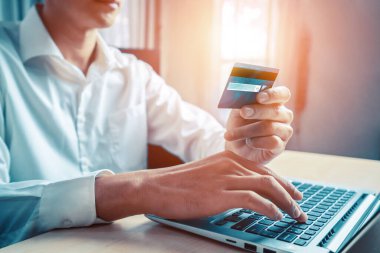 Genç adam, laptop bilgisayar başvurusu ya da web sitesinde online alışveriş yapmak için kredi kartı kullanıyor. E-ticaret ve online alışveriş konsepti. uds