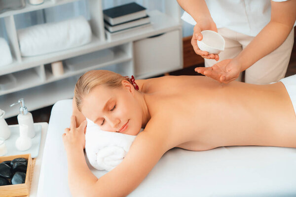 Массажист выливает ароматное масло на спину женщине. Массажист готовит масляный массаж для клиента в спа-салоне на роскошном курорте. Концепция массажа тела с ароматическим маслом. Quiescent