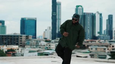 Profesyonel hipster çatıda gökyüzü avcısıyla ya da şehir siteleriyle break dans yapıyor. Sokak dansı performansı için yetenekli Asyalı hip-hop dansçısı. Modern dans. Açık hava sporu 2024 hiphop..