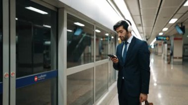 Proje yöneticisi tren istasyonunda şarkı seçmek için cep telefonu tutarken kulaklık takıyor. Zeki iş adamı bulanık geçmişi olan treni beklerken saati kontrol ediyor. Sevinçli..
