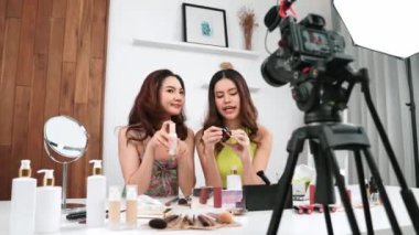 İki kadın nüfuzlu partner sosyal medya veya blog için canlı yayın yapan video klip inceleme derisi çekiyorlar. Canlı kozmetik stüdyo ışığı olan genç bir kız çevrimiçi pazarlama kayıt oturumu yayını için.