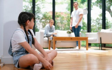 Stressed and unhappy young girl huddle in corner crying and sad while her parent arguing in background. Domestic violence at home and traumatic childhood develop to depression. Synchronos clipart