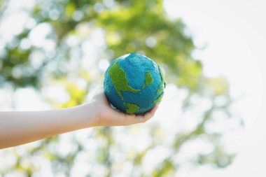 Dünya gezegenini ESG ilkesi ve çevre dostu enerjisiyle daha parlak bir gelecek için Dünya günü olarak el ele tutuşan genç çocuklar. Döngü