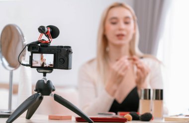 Sosyal medya için güzellik ve kozmetik video içeriği hazırlayan bulanık genç bir kadın. Güzellik etkileyicisiyle odaklanmış kamera ekranı izleyicilere ve takipçilere güzellik hizmetinin nasıl uygulanacağını gösteriyor. Blithe
