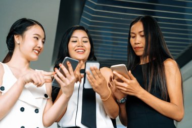 Üç kadın arkadaş ellerinde cep telefonuyla sohbet ediyorlar. Sosyal medya, dedikodu haberleri ve online alışveriş kavramı. uds
