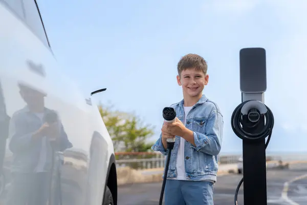 Zabawny Chłopczyk Celujący Kamerę Ładowarką Ładujący Ekologiczny Samochód Elektryczny Stacji — Zdjęcie stockowe