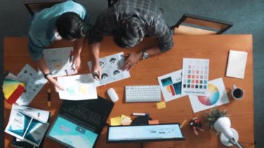 Takım ayakta dikilirken ve yorum yaparken müdürün fikir yazma konusunda üst düzey görüşü. Profesyonel tasarımcı logosu renk paletine bakarken ve renkli kalemle fikri kağıda yazarken. Sempozyum.