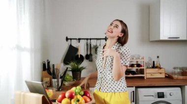 Enerjik beyaz anne kahvaltı için salata pişirirken ve yemek pişirirken elinde kepçeyle şarkı söylüyor. Sağlıklı yemek yapmaya hazırlanırken müziğe yönelen mutlu ev sahibi. Pedagoji.