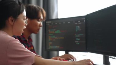 Yavaş çekim arkası yazılım geliştirici mühendisi bilgisayar programlama için birlikte çalışarak hata ayıklama kodunu çözüyor, ofiste monitörde karmaşık algoritmaları çözüyor. Filizlenen