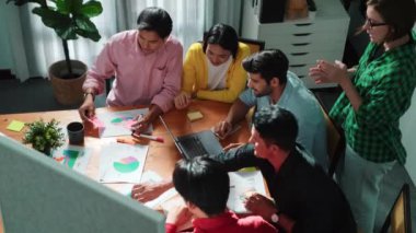 Çeşitli insanlardan oluşan bir grup, el çırparken yapışkan bir notla pazarlama planı yapıyor. Top view dizüstü bilgisayarla çalışırken borsa yatırımını tartışıyor ve konuşuyor. Cemaat.