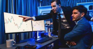 Borsa simsarları panorama manzaralı yüksek kar tablosu yatırımlarına bakıyor, geceleri monitörde analiz ediyorlar. İş yerinde finansal teknoloji gelişimini neon ışığında tartışma kavramı. Satılabilir.