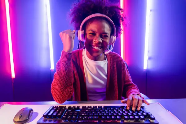 stock image Gaming streamer, African girl playing online fighting with Esport skilled team wearing headphones in neon color lighting room. Talking other players planing strategies to win competitors. Tastemaker.