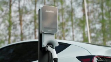 EV elektrikli araç EV şarj istasyonu ulusal park veya açık hava orman manzaralı. Sonbahar mevsimi ormanlarında çevre dostu EV arabalarla doğal koruma. Yükselt