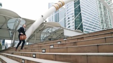 Kafkasyalı zeki işadamı şehir manzarası ile çevrili merdivenleri çıkıyor. Hırslı proje yöneticisinin modern inşaatta zorlu bir iş ya da yatırım fırsatı bulması. Urbane.