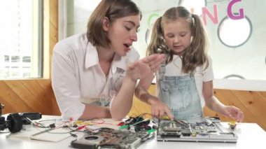 Genç, zeki, beyaz bir öğretmen öğrencilere elektronik kurulun bir parçasını öğretiyor. Uzman kız dijital elektrikli aletleri öğreniyor ve cips ve kablolarla ana kartı tamir ediyor. Etkinlik.