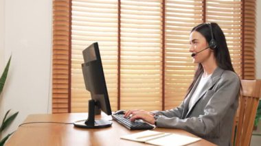 Kadın çağrı merkezi operatörü ya da müşteri hizmetleri çalışanı, müşteriye yardım etmek için kulaklıkla konuşurken çalışma alanı üzerinde çalışıyor. Profesyonel modern iş hizmeti. Blithe