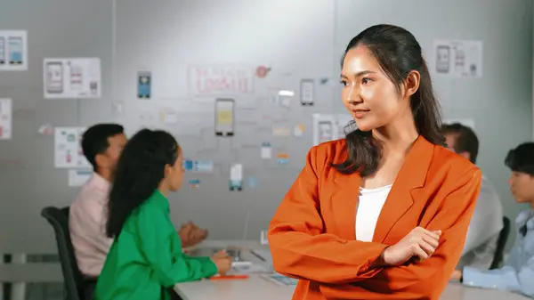 Asian professional businesswoman standing with confident at creative business meeting. Beautiful confident leader posing while diverse business people discussion about using Ux and Ui design