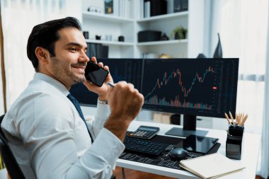 Trader businessman calling to consultant or partner with two stock exchange investment, compare data analysis to invest high profit value dynamic financial technology stock market at office. Surmise. clipart