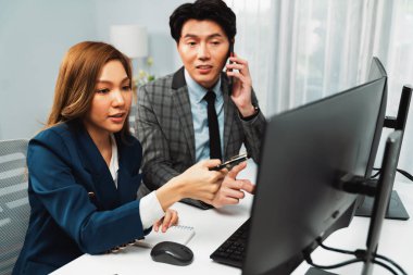 İş ortağıyla cep telefonundan arayan işadamı bilgisayardaki kadın iş arkadaşıyla hisse senedi değer veri tabanını hesaplarken şirket değerini analiz ediyor ya da güncel alım yapıyor. İnfobahn.