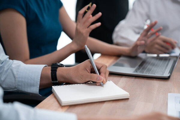 Secretary taking notes on notebook at corporate meeting with group of multiracial business people discussing together in meeting room. Diversity in professional meeting at modern office. Concord