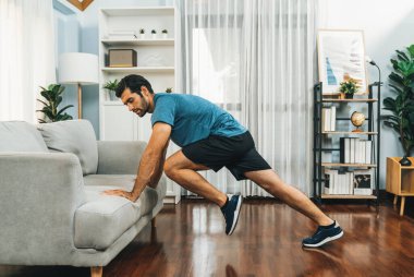 Atletik vücut ve aktif sporcu, sağlıklı vücut çalışma yaşam tarzı konsepti olarak neşeli ev egzersizlerinde kas kazanma egzersizi yapmak için mobilyaları kullanıyor..