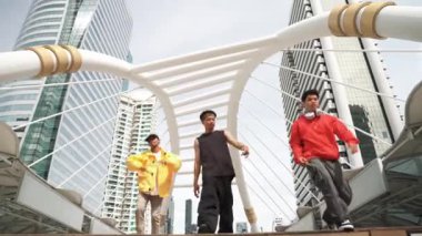 Bir grup mutlu break dansçı şehirde dans ederken merdivenlerden iniyor. Profesyonel hipster kameraya bakarken enerjik adımlar atar. Düşük açılı kamera. Açık hava sporu 2024. Yumuşak bir şekilde..