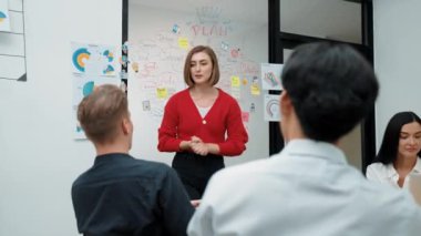 Yetenekli genç ve güzel iş kadını, yaratıcı iş toplantısında yakışıklı yönetici dinlerken zihin haritalama ve istatistiksel grafik kullanarak pazarlama fikrini kendine güvenle sunuyor. Tertemiz..