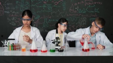 Mesleki çeşitlilik gösteren öğrenci, STEM fen dersinde, kimyasal teoriyle karatahta deneyimi yaşıyor. Genç bir delikanlı biyo-kimyasal çözeltiyi mikroskop ile masada karıştırıyor. Öğretim