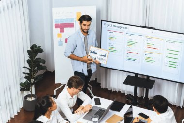 Proje yöneticisi monitörde proje yönetimi yazılım görüntülemesi, proje görevinin ilerlemesini izlemek ve toplantı masasında program planı yapmak suretiyle ekiple iletişim kurar ve işbirliği yapar. Tedbirli