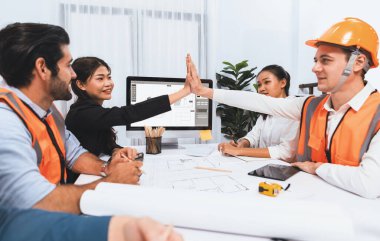 Çeşitli inşaat mühendisi ve müvekkil grupları, mimari proje üzerinde başarılı bir anlaşma yaptıktan, inşaat planını gözden geçirdikten ve toplantı masasında plan oluşturduktan sonra kutlama ve beşlik çakışma yaptılar.